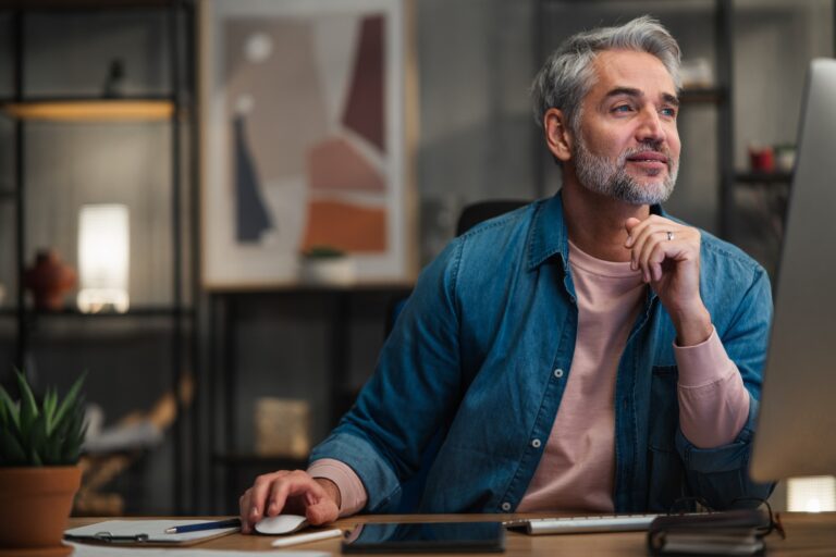 Mature man working on computer at desk indoors in office