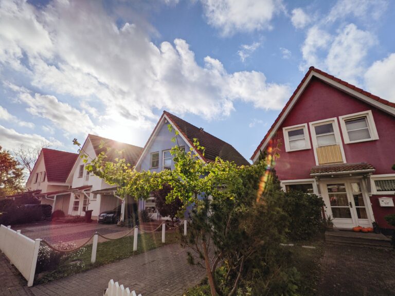 A row of modest houses on a sunny street with trees outside