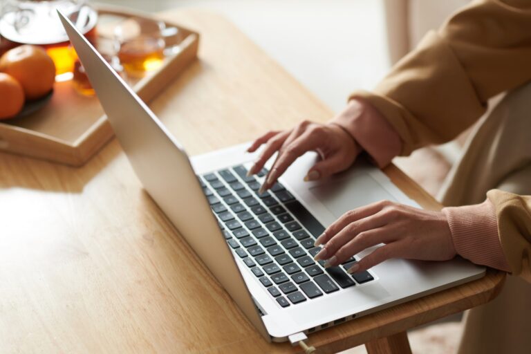 Woman typing on a laptop on a wooden table